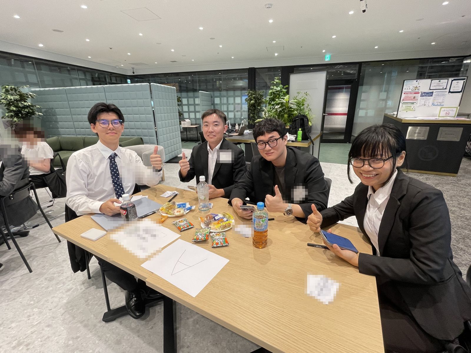 チームのテーブルで、学生たちがカメラに向かって親指を立てている様子