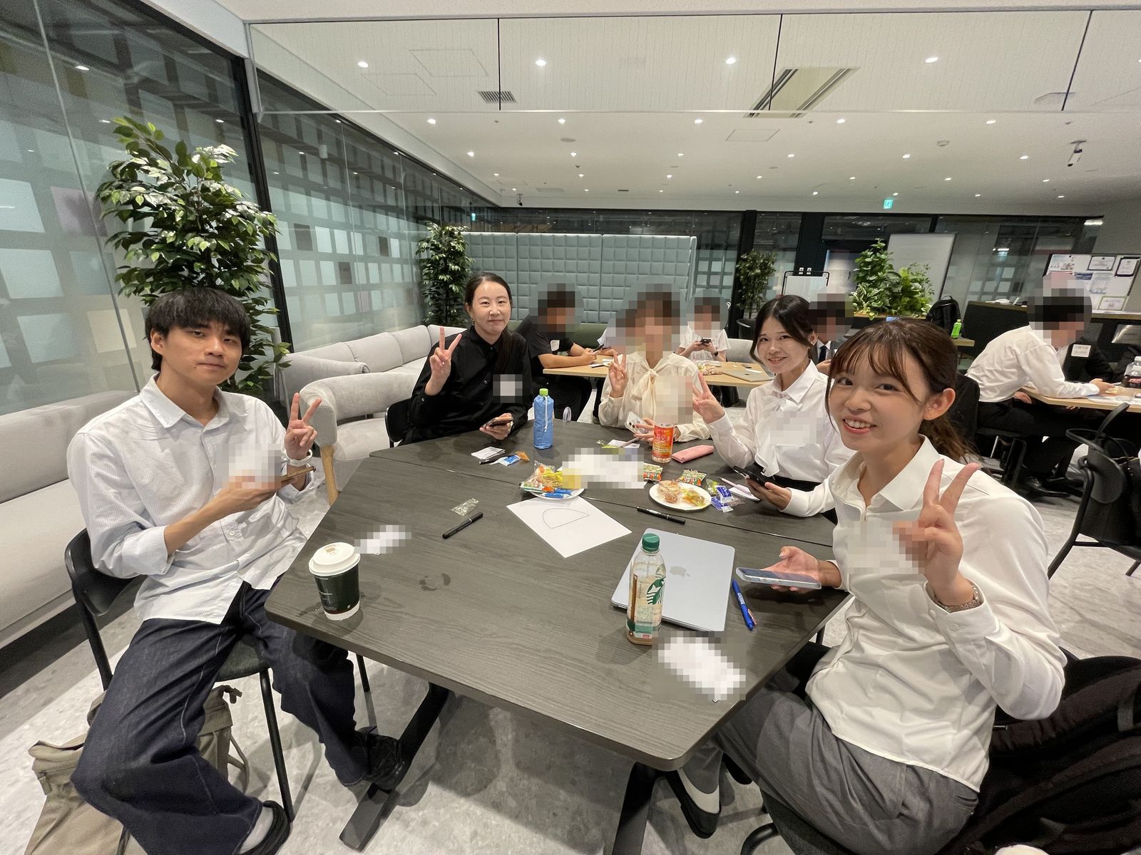 チームのテーブルを囲んで、学生たちがピースをしている様子